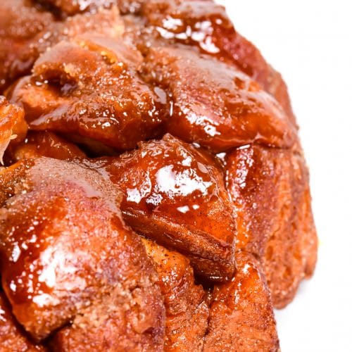 photograph of golden brown monkey bread with a caramel glazed on a white platter. // addapinch.com