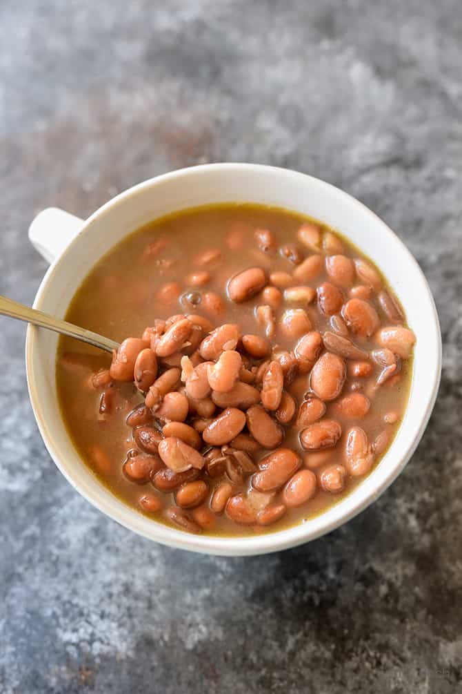 White mug holds spoon and pintos on a granite counter. 