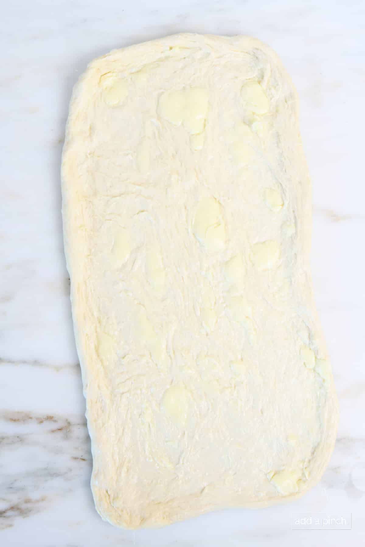 Rolled pizza dough covered with butter.