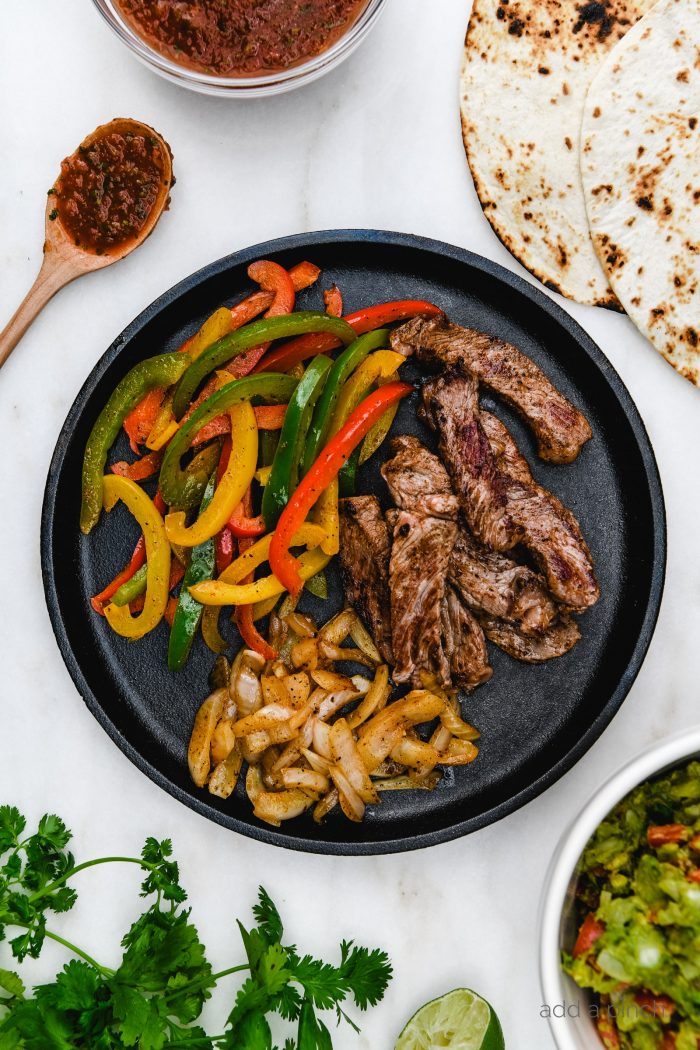 Ribeye Fajitas with peppers, onions, and served with tortillas, guacamole, and restaurant style salsa. // addapinch.com