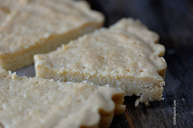 Triangle slices of thick shortbread sits on a wooden tray.