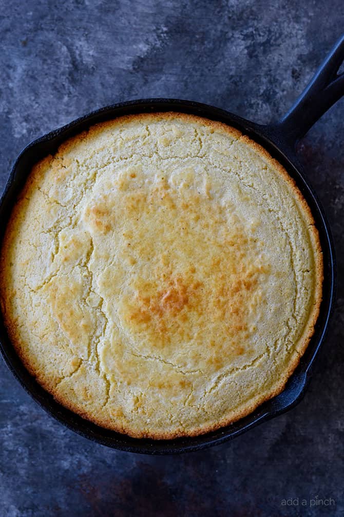 Cast iron skill holds browned cornbread with crisp edges. 