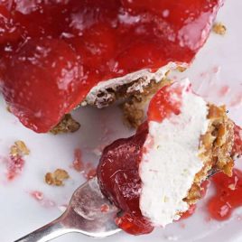 Plate with piece of strawberry pretzel salad cut with a fork.