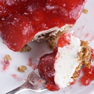 Plate with piece of strawberry pretzel salad cut with a fork.