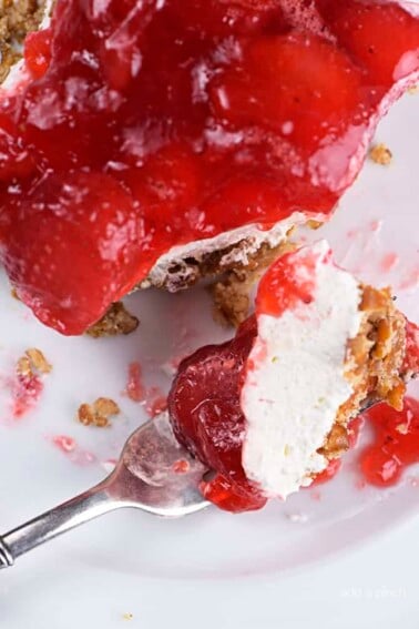 Plate with piece of strawberry pretzel salad cut with a fork.