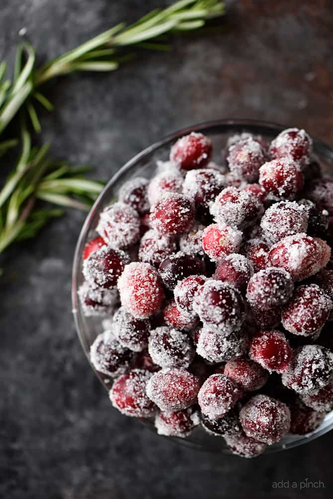 Bowl of beautiful Sugared Cranberries on grey stone background // addapinch.com
