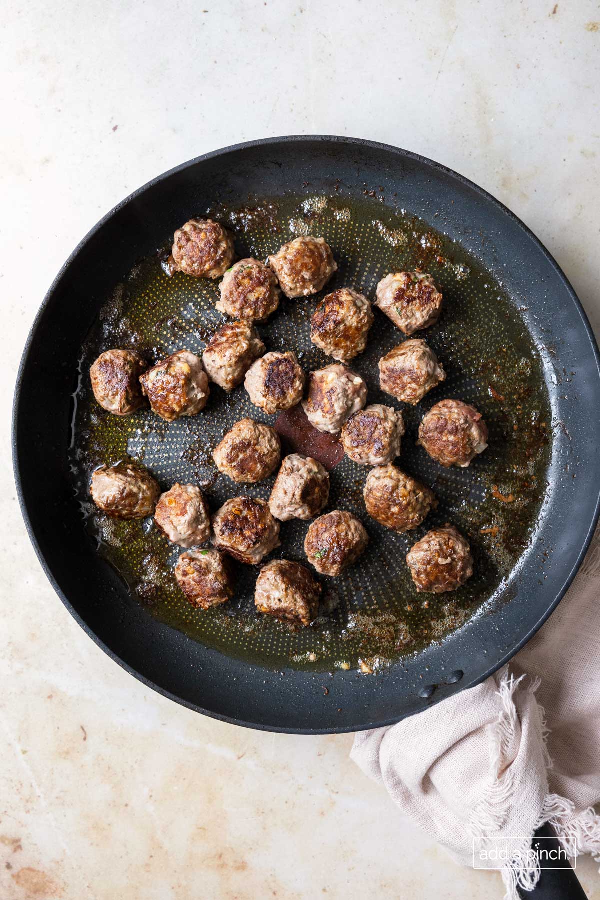 Cooked meatballs are cooked until brown in a skillet. 