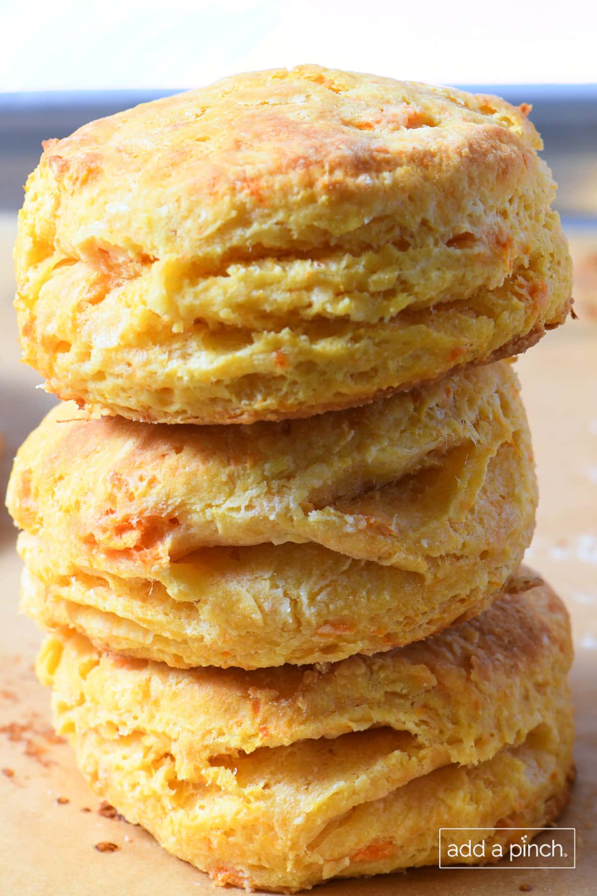 Three sweet potato biscuits stacked on a baking sheet lined with parchment paper.