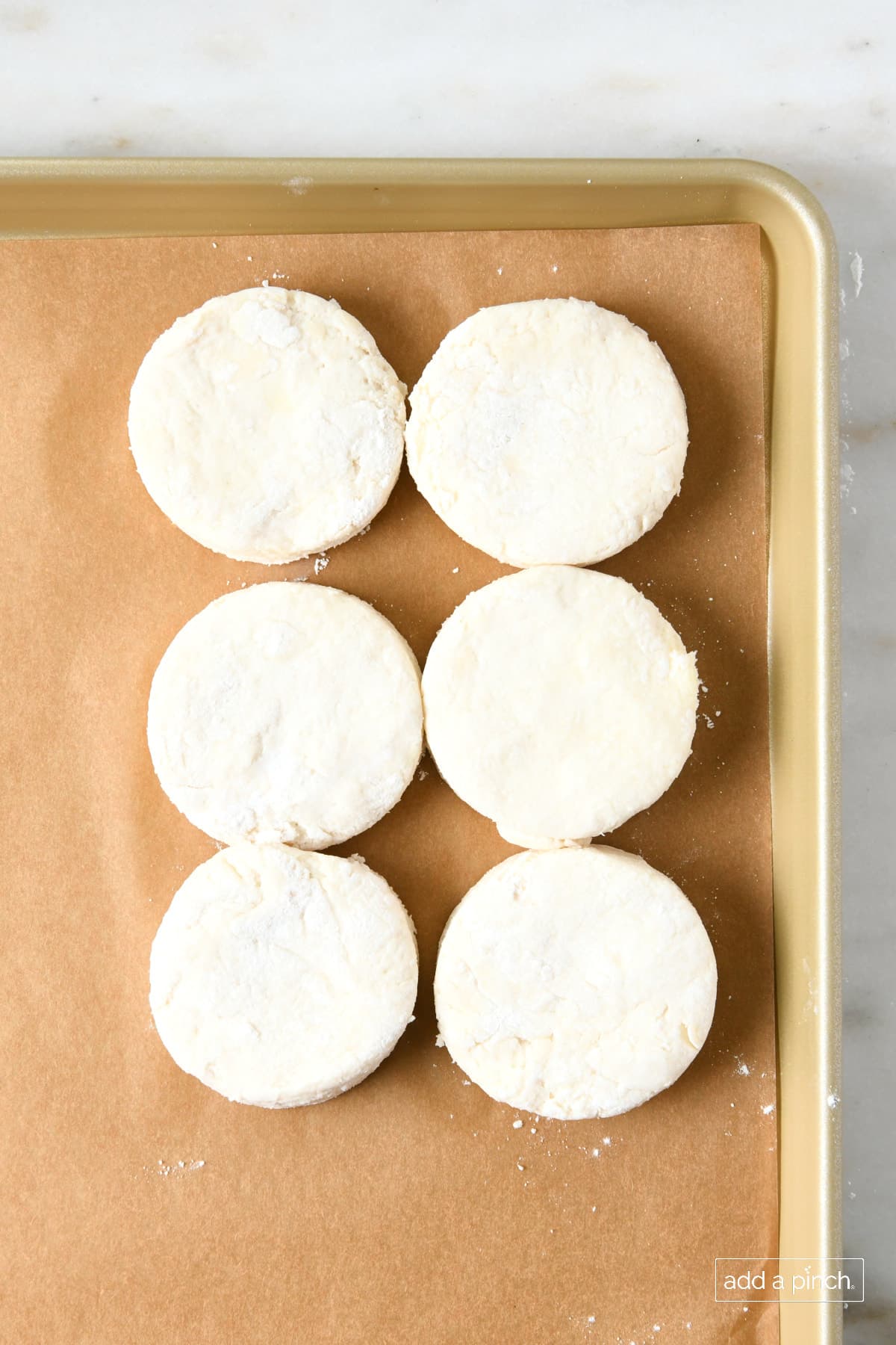 Baking pan with parchment and biscuits ready to bake. 