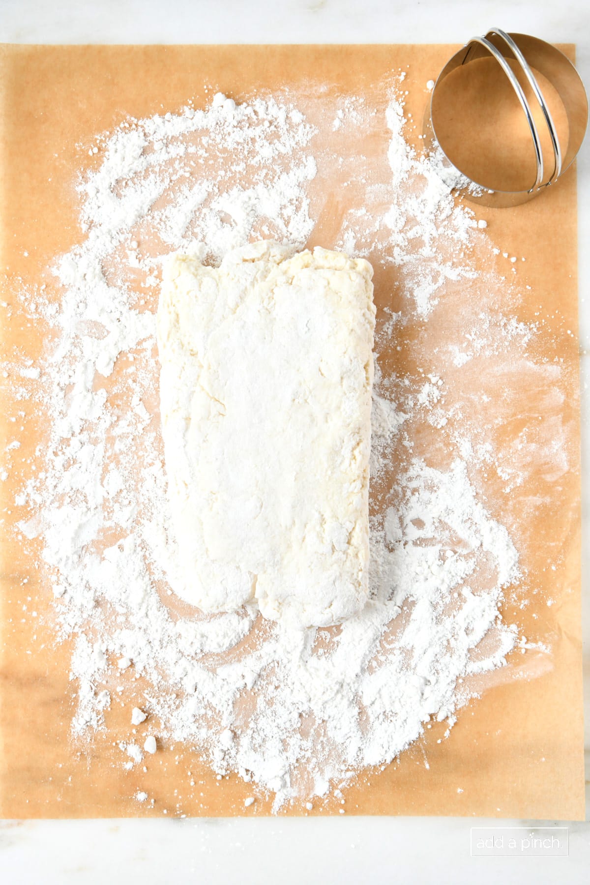 Biscuit dough that's been patted and folded and ready to cut with biscuit cutter.