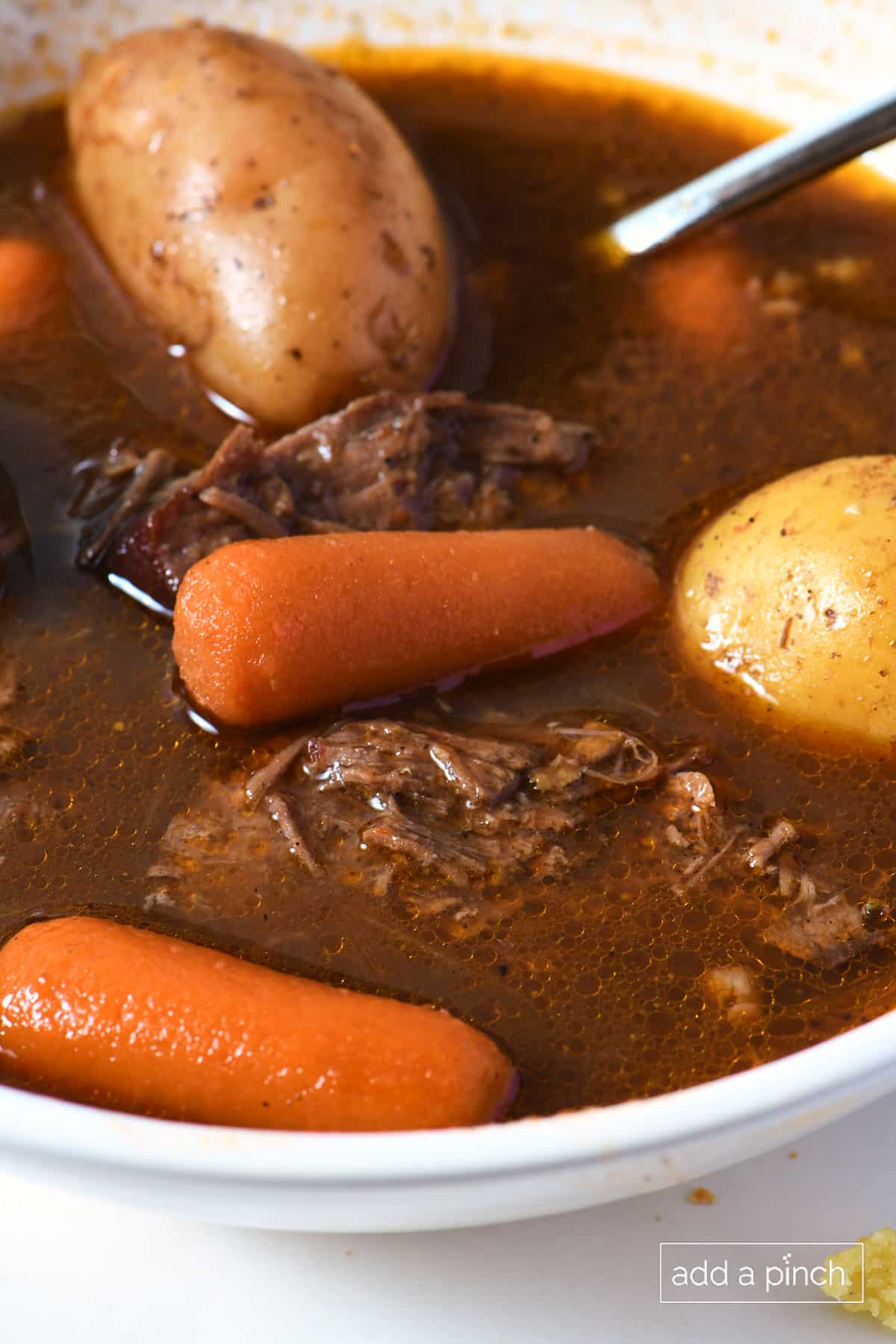 White soup bowl filled with venison stew with potatoes, onions, carrots.