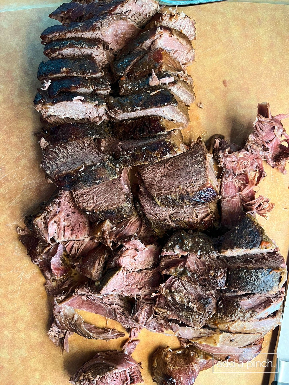 Chopped deer roast on cutting board with knife on the side.