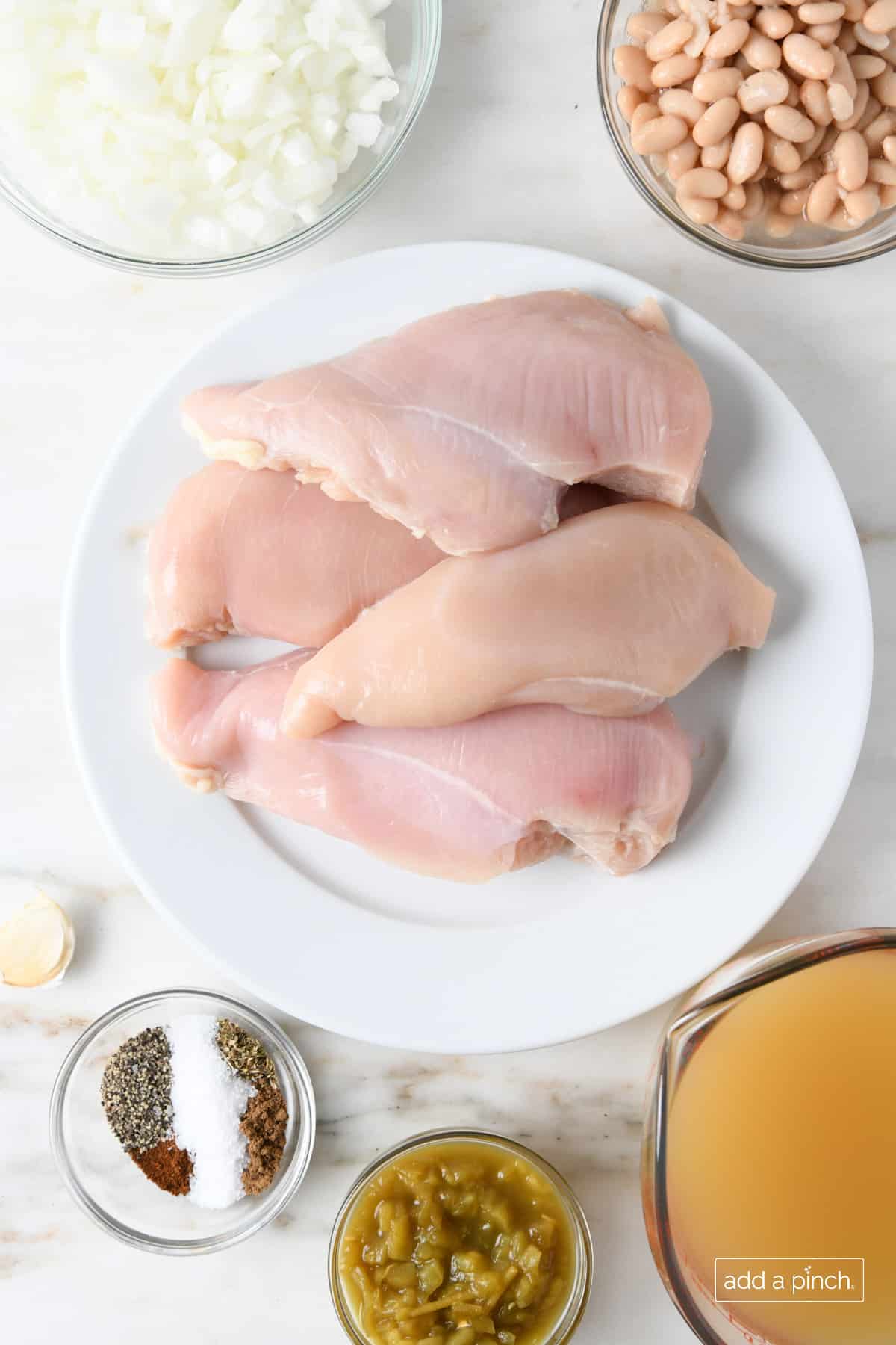 Ingredients for white chicken chili on a white marble counter.