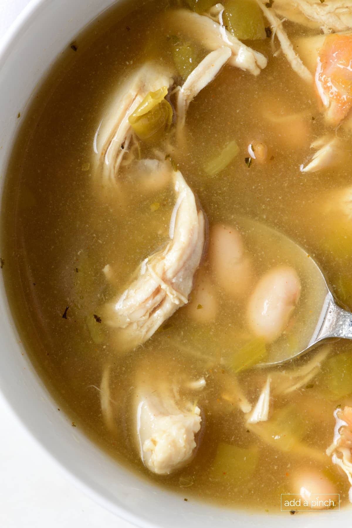 White Chicken Chili in a white soup bowl with a silver spoon.
